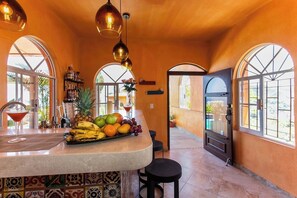 A kitchen with a fruit display, a blender, and a martini glass.