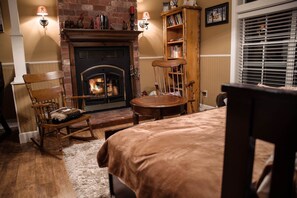 Cozy room with a traditional fireplace, comfortable seating area, and a bookshelf for reading.