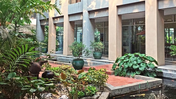 Een binnenplaats met een waterpartij, potplanten en een gebouw met meerdere verdiepingen en balkons.