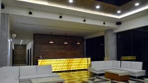 A modern lobby with a reception desk, white sofas, and a checkered floor.