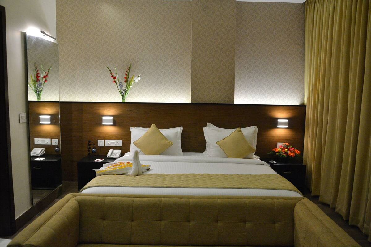 A hotel room with a large bed, two bedside tables, a mirror, and a nightstand with a telephone.