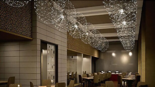 A modern restaurant with a high ceiling and unique spherical light fixtures. Tables are arranged in a spacious layout with ample seating.