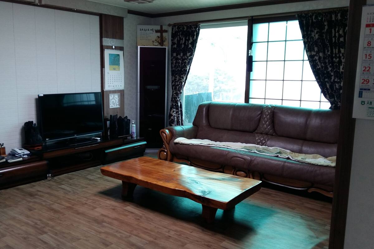 A living room with a television, a sofa, and a wooden coffee table.