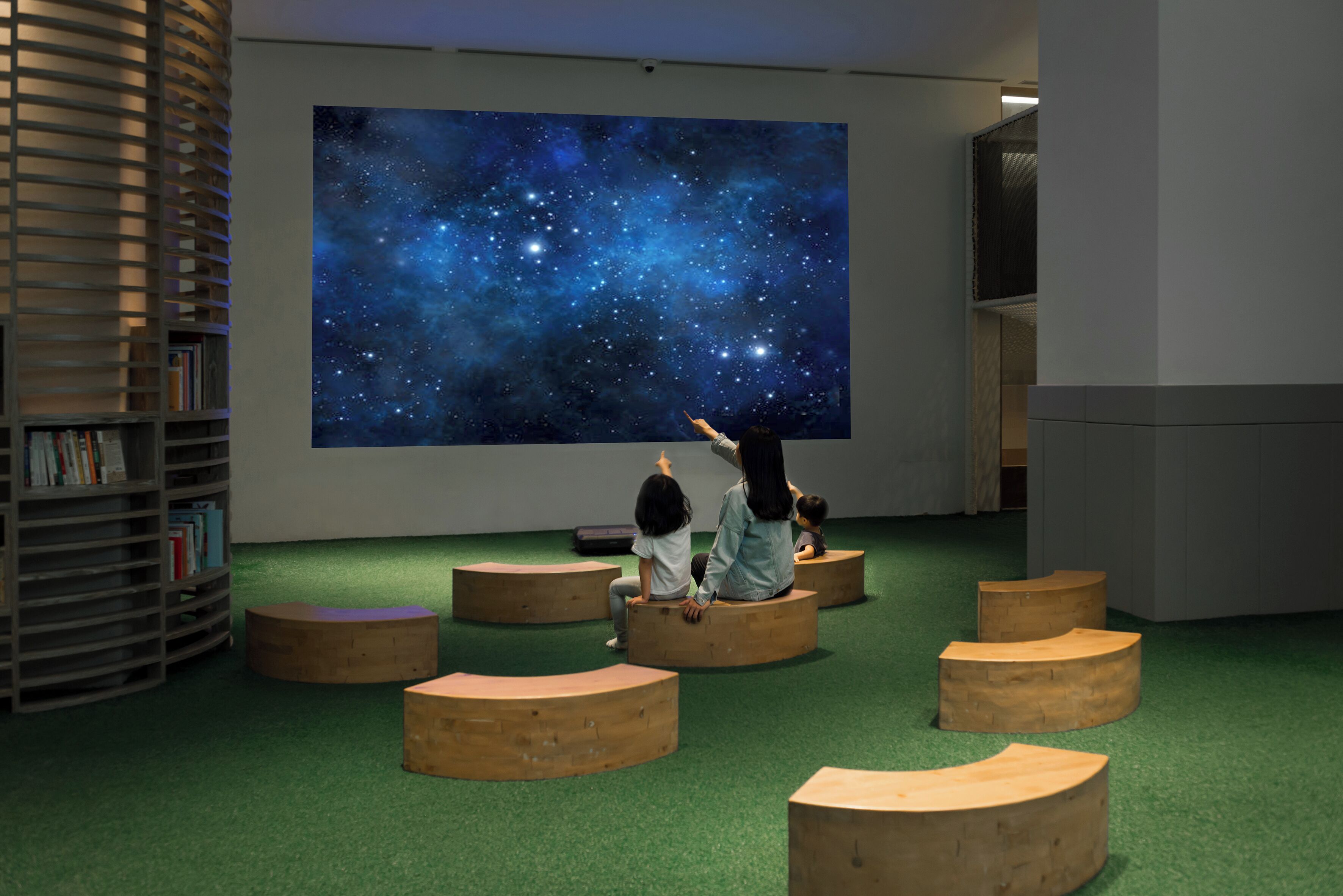 A room with a large starry sky mural, wooden circular seating, and a bookshelf.
