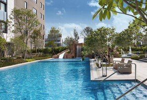 Una piscina al aire libre, sombrillas, sillones reclinables de piscina