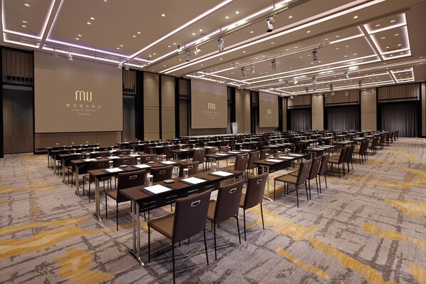 Un salón de conferencias con filas de mesas y sillas, equipado con micrófonos y proyectores, en el HOTEL JIAO XI en Taiwán.