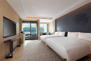 Quarto de hotel com duas camas, televisão, varanda e uma janela grande.