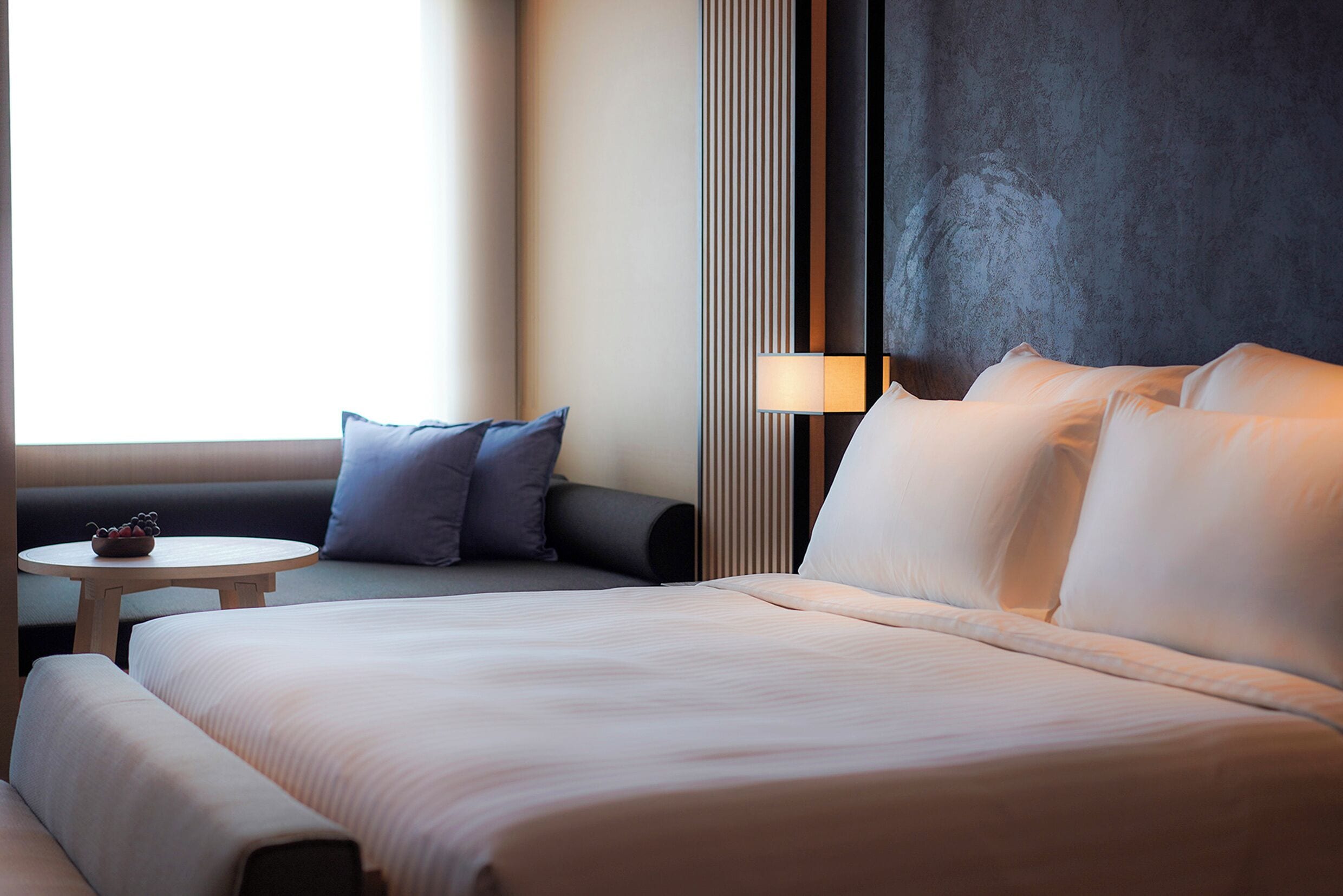 A hotel room with a large bed, a small round table, and a sofa.