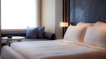 A hotel room with a large bed, a small round table, and a sofa.