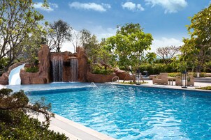 Una piscina al aire libre, sombrillas, sillones reclinables de piscina
