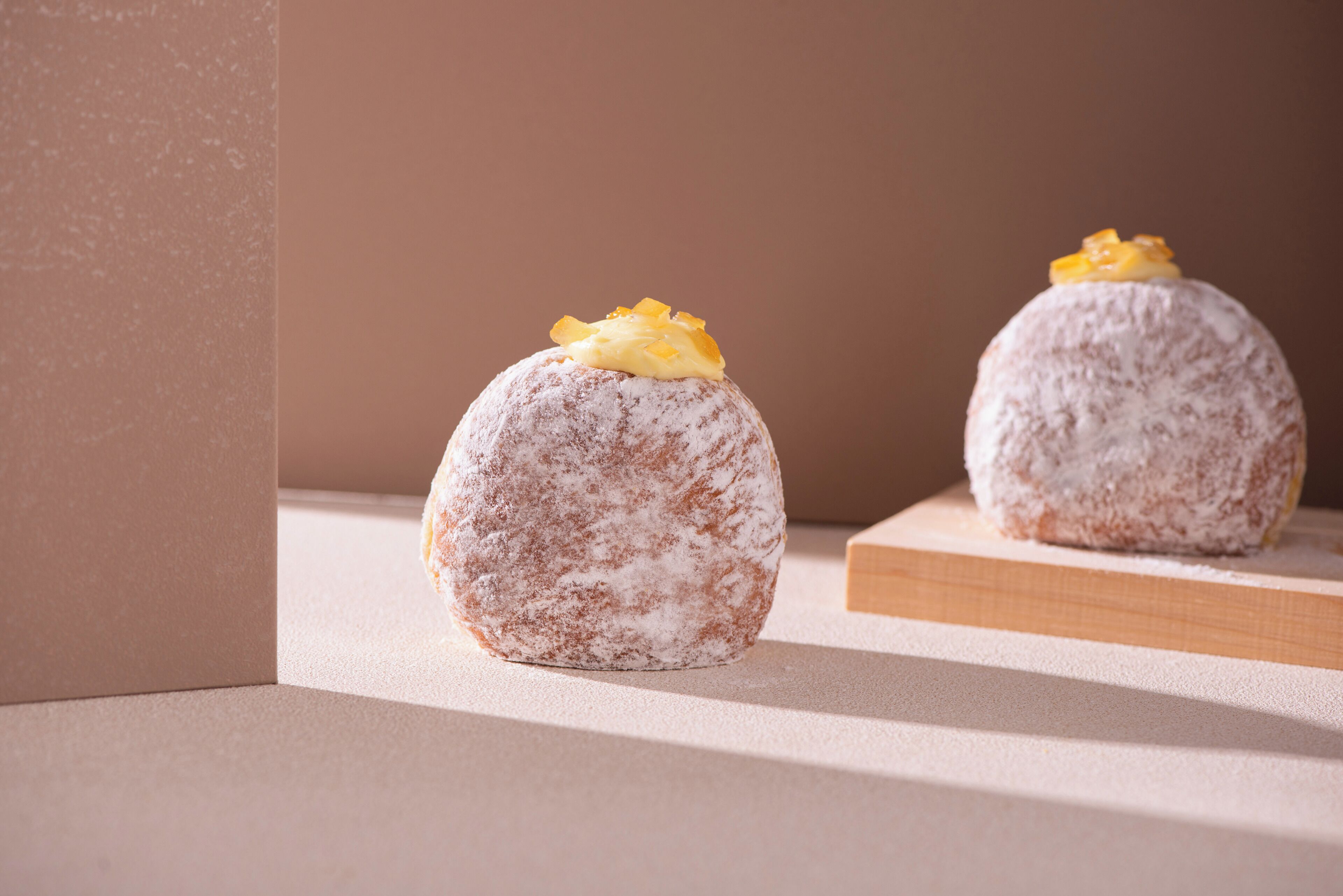 Two spherical pastries on a wooden surface with a plain background.