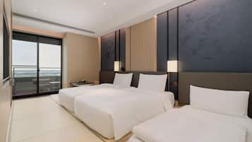 A hotel room with two beds, a balcony, and a city view.