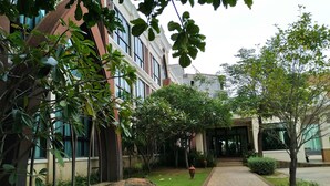 A pathway leading to a building with large windows and a covered entrance. - Srilamduan Hotel (Sisaket)