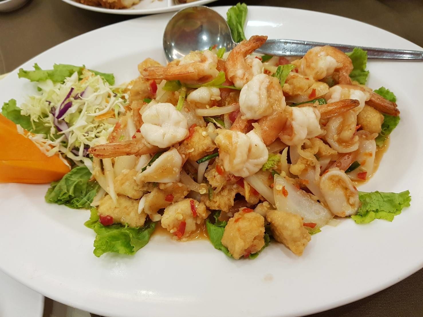 Un plato de comida con camarones, vegetales y una ensalada.