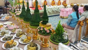 A ceremonial setting with monks seated in front of a decorated altar, surrounded by offerings and traditional food arrangements. - Srilamduan Hotel (Sisaket)