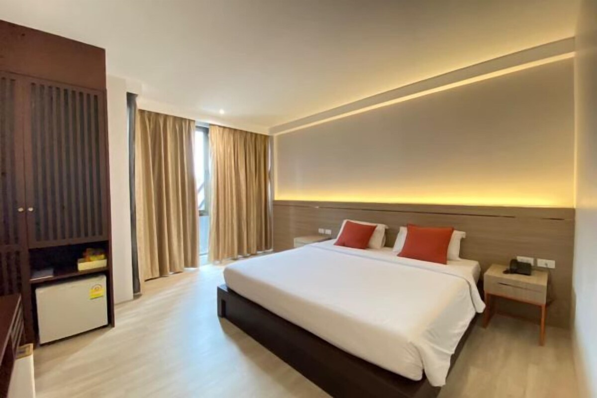 Habitación de hotel con una cama grande, una mesita de noche, un armario y vistas al exterior.