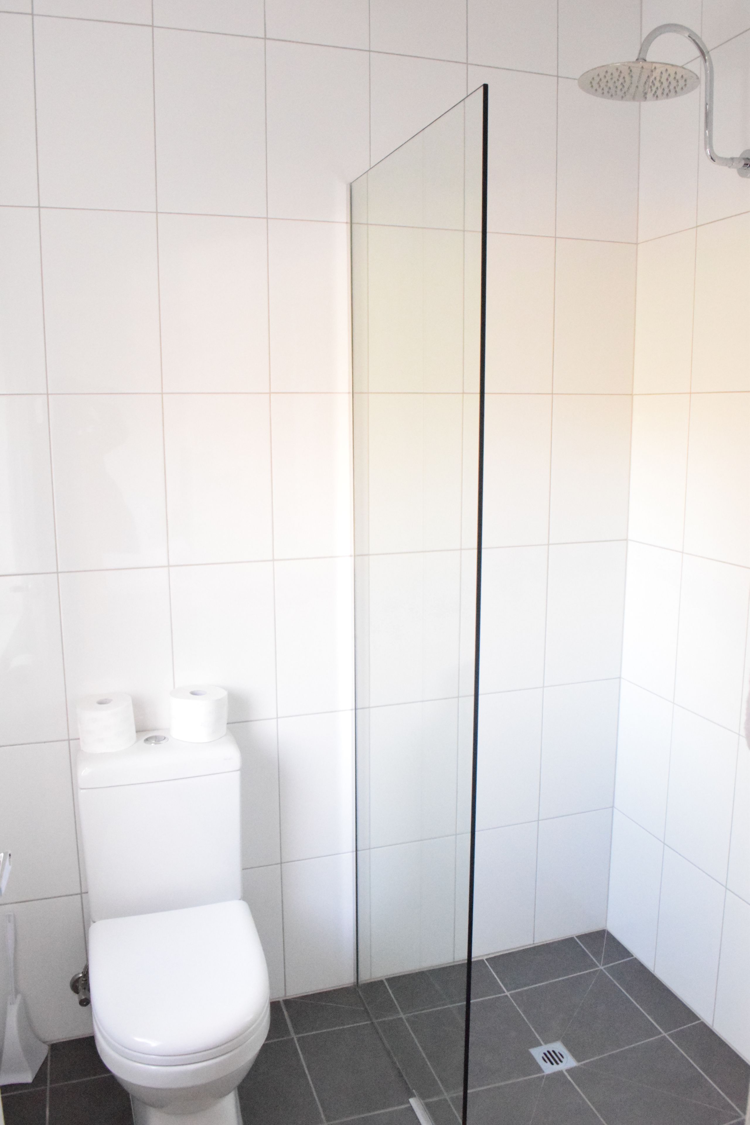 A bathroom with a white toilet, a shower enclosure, and a tiled floor.