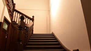 Una escalera de madera con barandilla y una puerta al final.