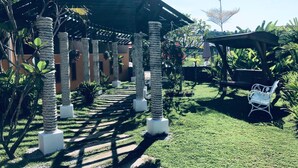 Un espacio al aire libre cubierto con una pérgola, palmeras y una silla blanca.