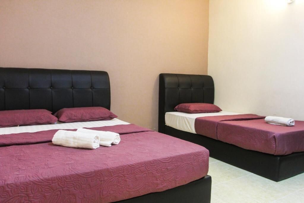 Habitación de hotel con dos camas, cada una con cabecero negro y ropa de cama roja.