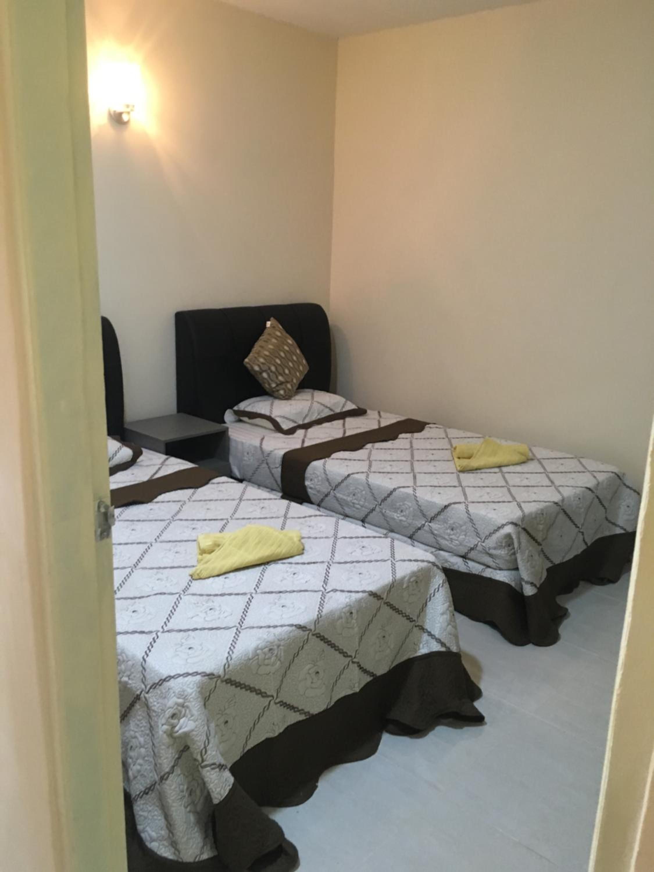 A room with two beds, each with a patterned bedspread and a pillow.