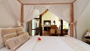 Un dormitorio con cama a dosel, vista al comedor y una pequeña mesa con toallas.