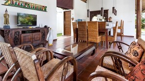 Amplia sala de estar con televisor, muebles de madera y un elemento decorativo en la pared.