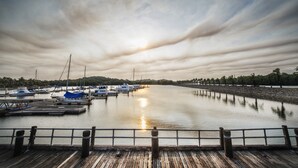 A wooden dock leading to a marina with boats and a calm water body. - Sebana Cove Resort (Bandar Penawar)