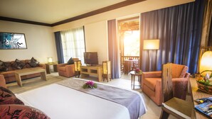 A hotel room with a large bed, a sofa, a desk with a television, and a balcony with a table and chairs. - Sebana Cove Resort (Bandar Penawar)