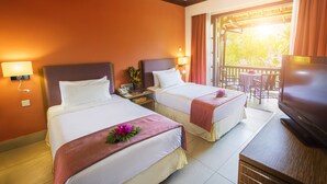A hotel room with two beds, a TV, a balcony with a table and chairs, and a view of the outdoors. - Sebana Cove Resort (Bandar Penawar)