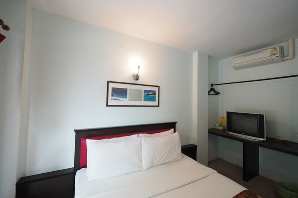 A hotel room with a bed, a TV, and a framed picture on the wall.