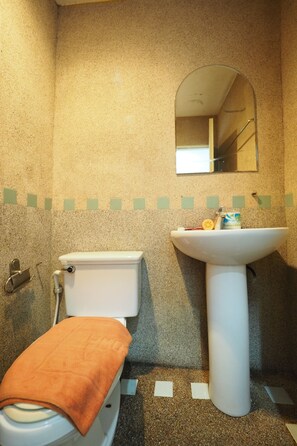 A bathroom with a toilet, sink, and mirror.