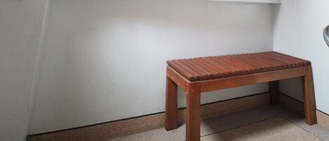 Una habitación con un banco de madera, un cuadro de una escena de playa y una ventana.