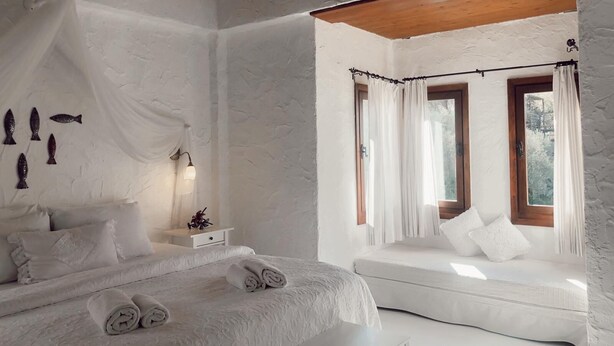 A bedroom with a bed, a sofa, and a window with curtains. - Jakamar Alacati (Cesme)