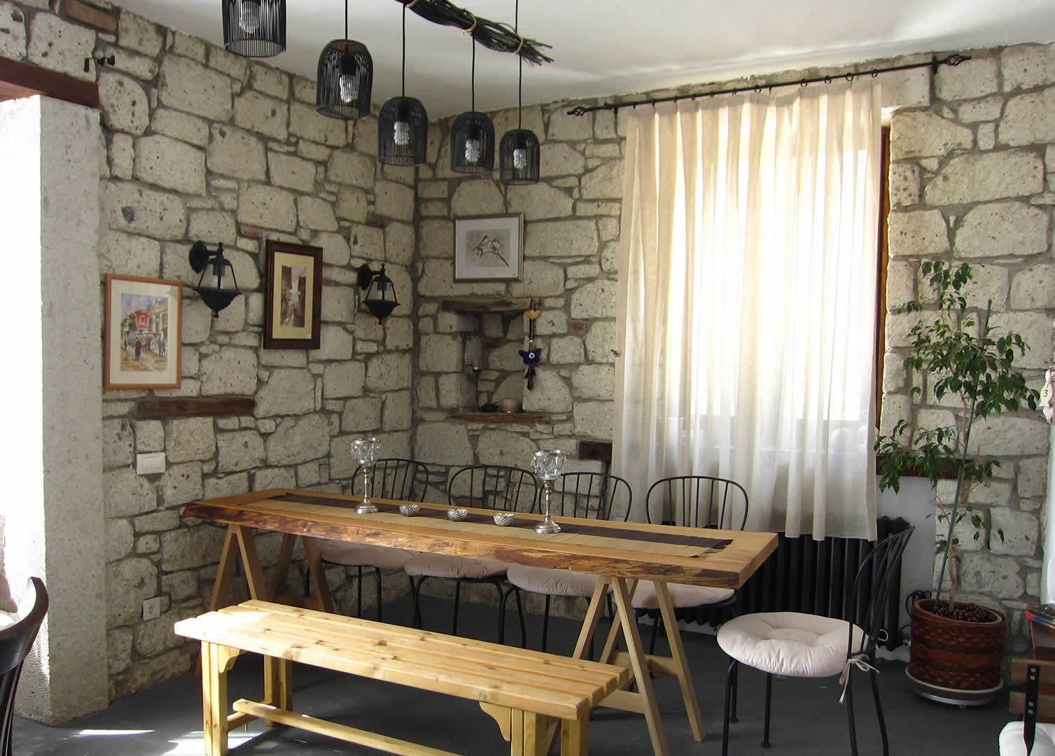 Un coin repas rustique avec un mur en pierre, une table en bois et des chaises.