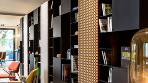 Uma biblioteca moderna com estantes pretas, um pilar estampado e um banco.