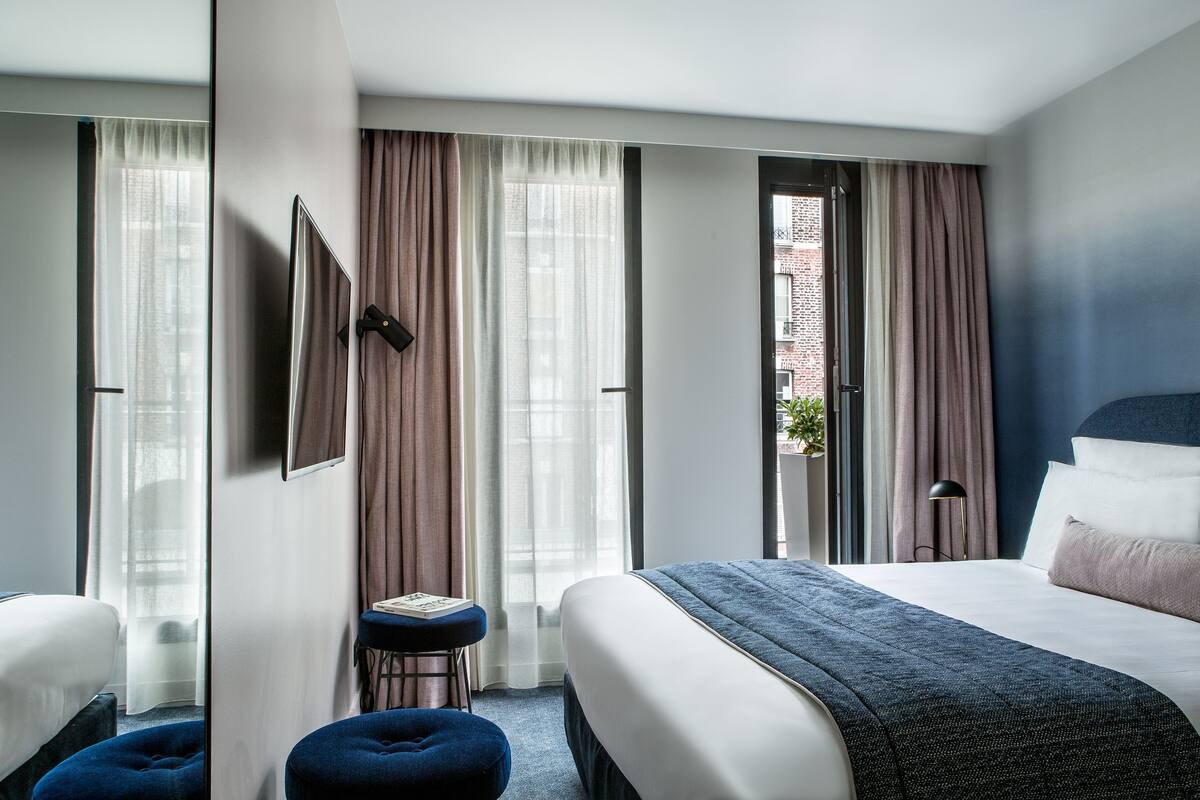 A hotel room with a large bed, a desk, and a view of a brick building.