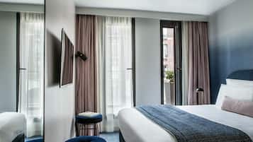 Ett hotellrum med en stor säng, ett skrivbord och utsikt över en byggnad med fasad av tegel.