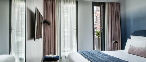 A hotel room with a large bed, a desk, and a view of a brick building.