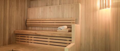 A wooden sauna with benches and a bench seat, and a towel rack with towels.