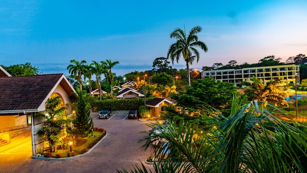 Un resort con varias edificaciones tipo bungalow, un camino pavimentado y exuberante jardinería tropical.