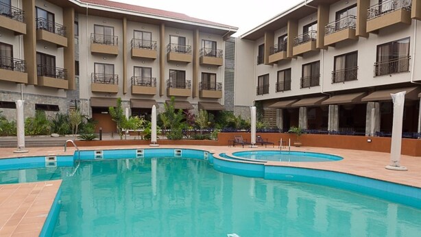 A hotel with a swimming pool, multiple balconies, and a courtyard with plants.