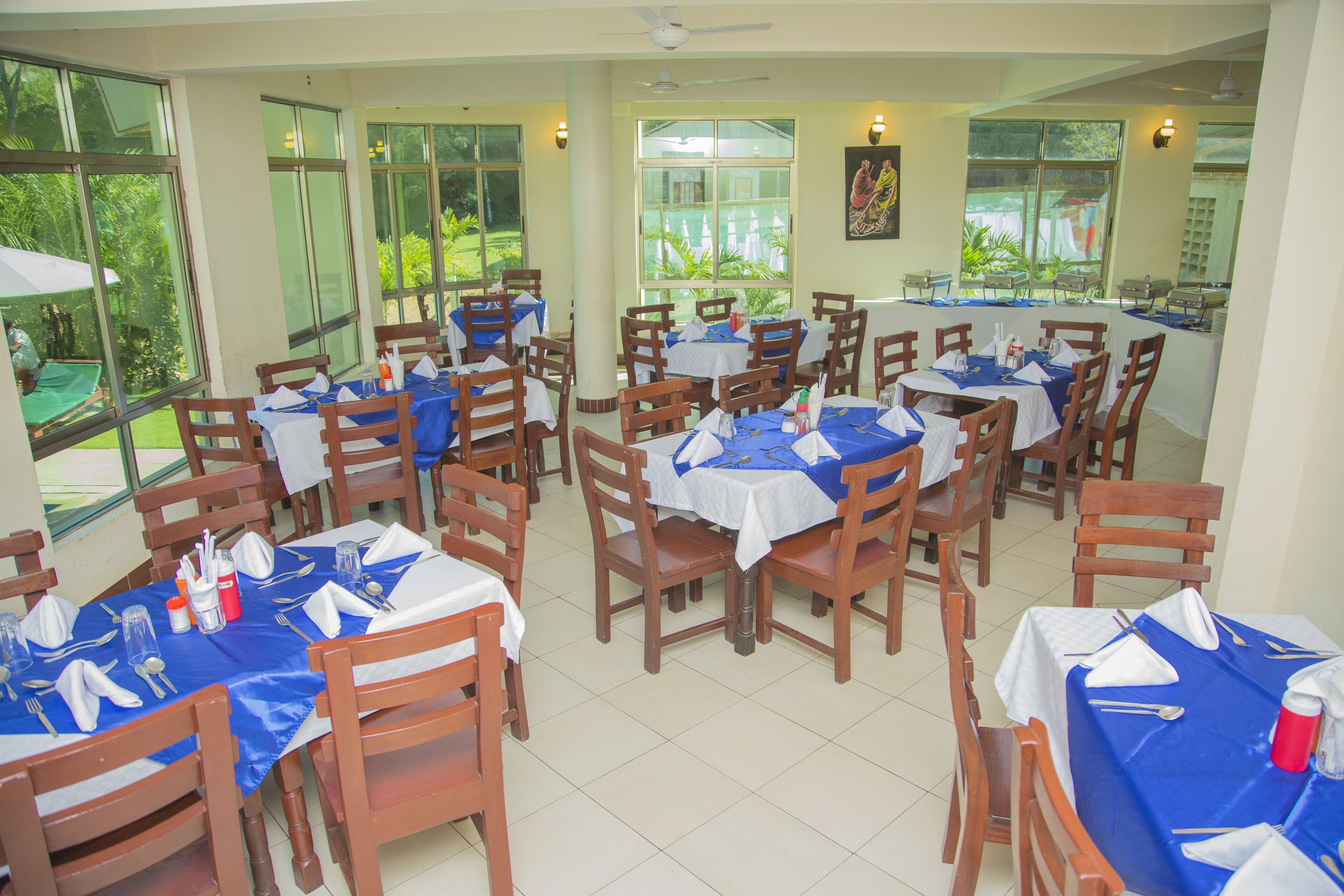 A restaurant with multiple tables and chairs, large windows, and a ceiling fan.