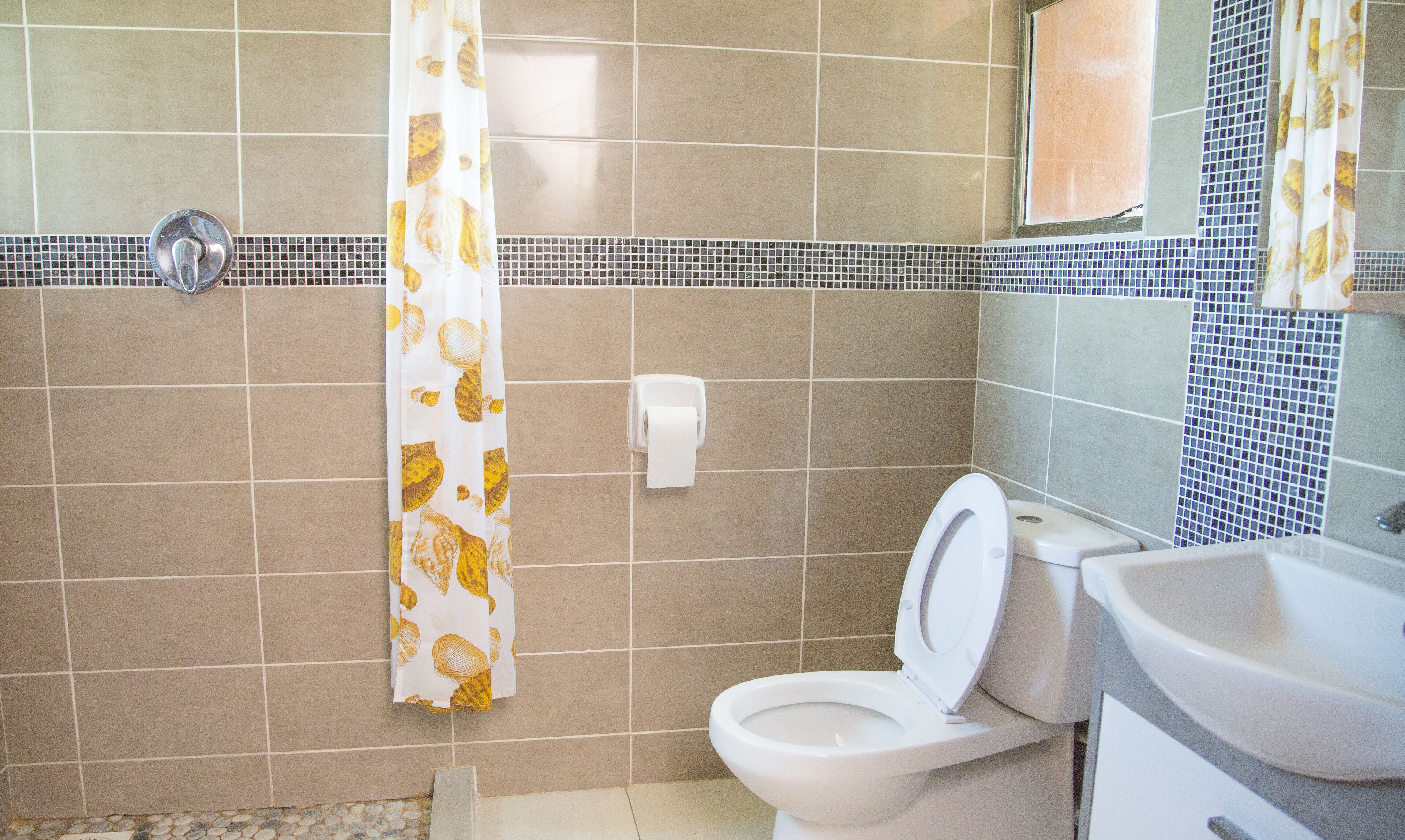 A bathroom with a toilet, sink, and shower curtain.