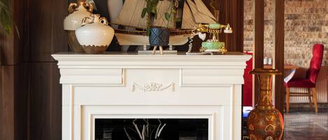 A fireplace with a mantel, a small table, and a decorative vase.