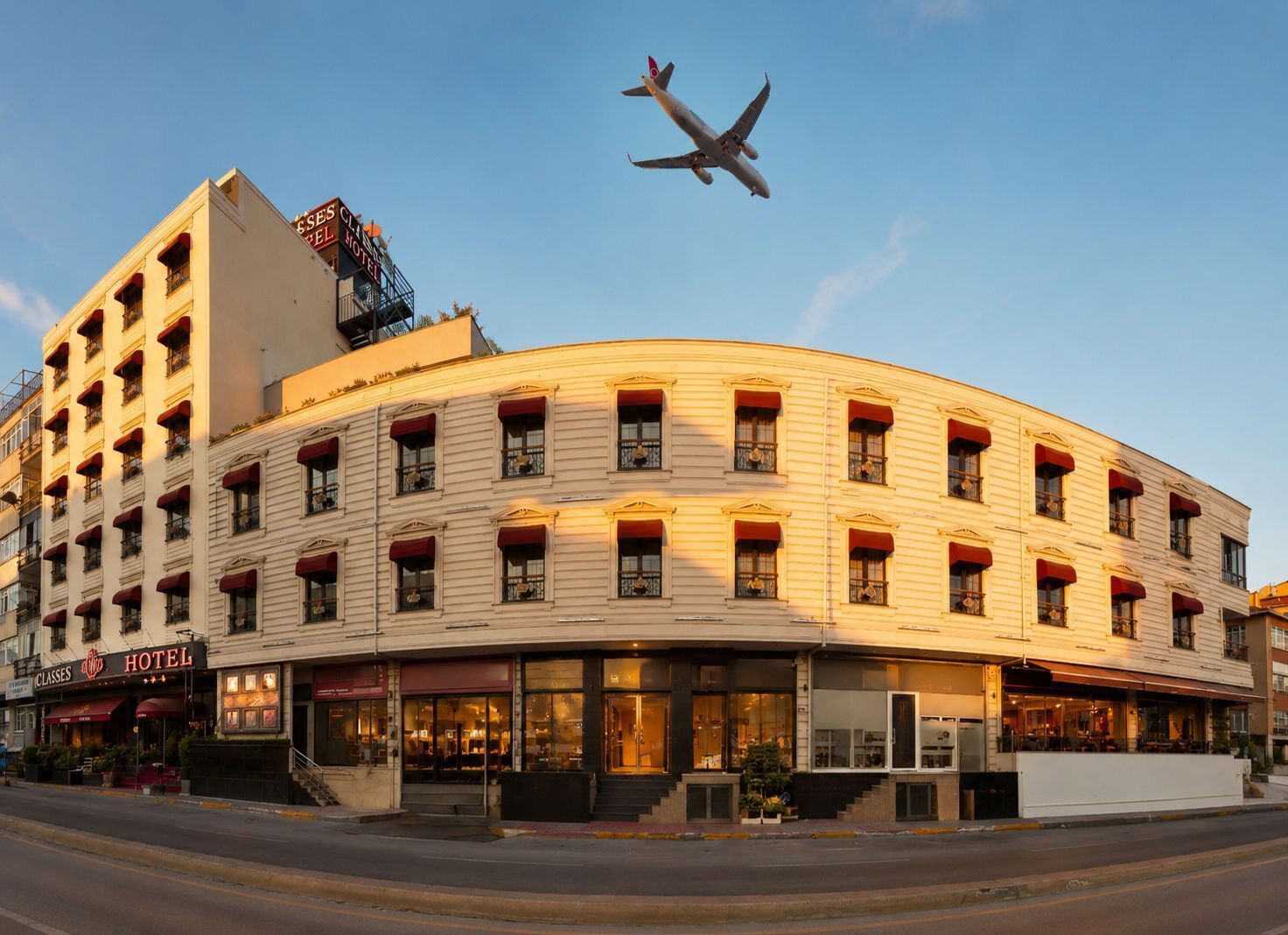 A hotel with a curved facade, multiple windows with red awnings, and a visible sign for 'CLASSES HOTEL.'