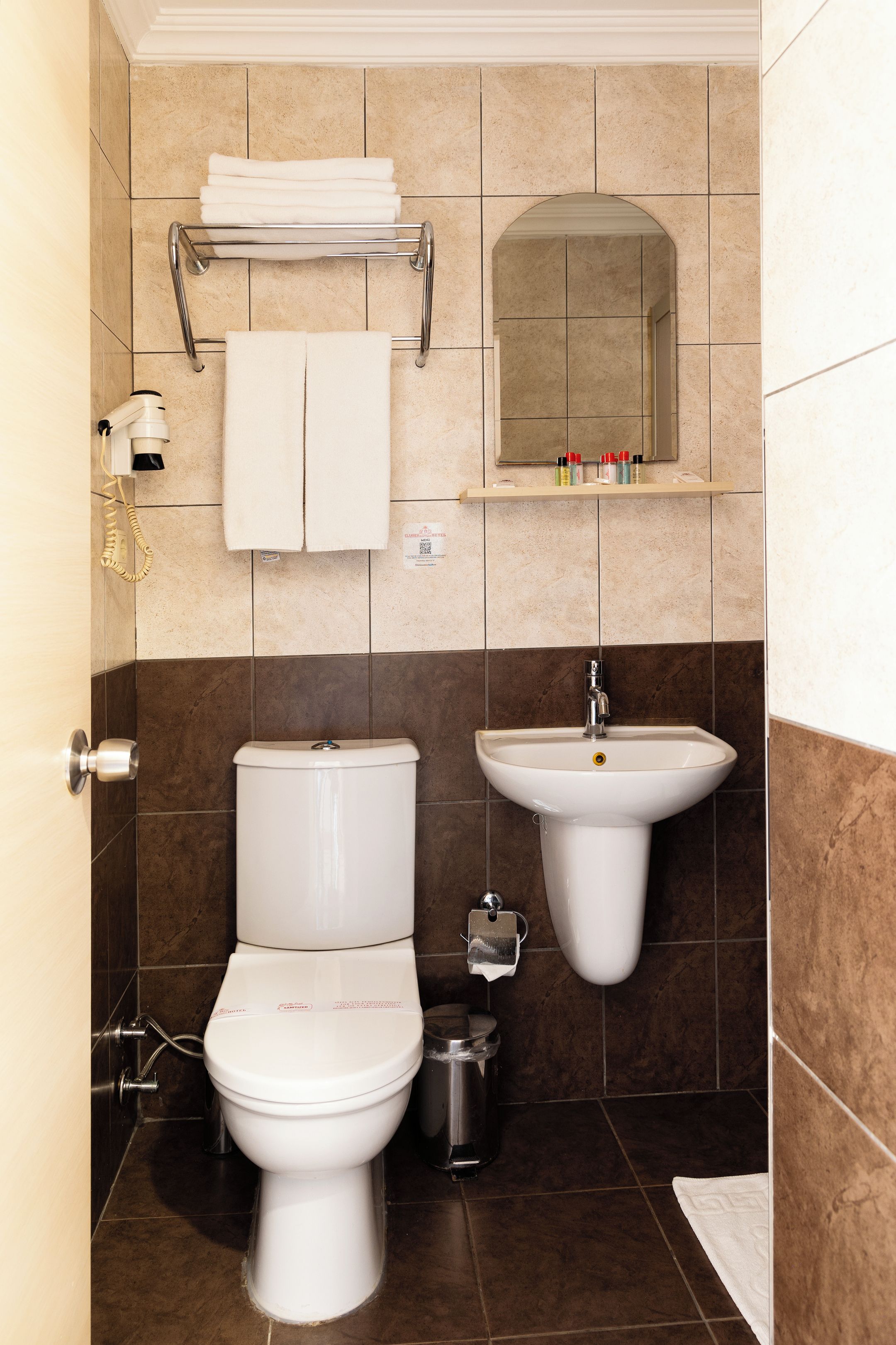 Une salle de bain équipée de toilettes, d’un lavabo et d’un porte-serviettes.
