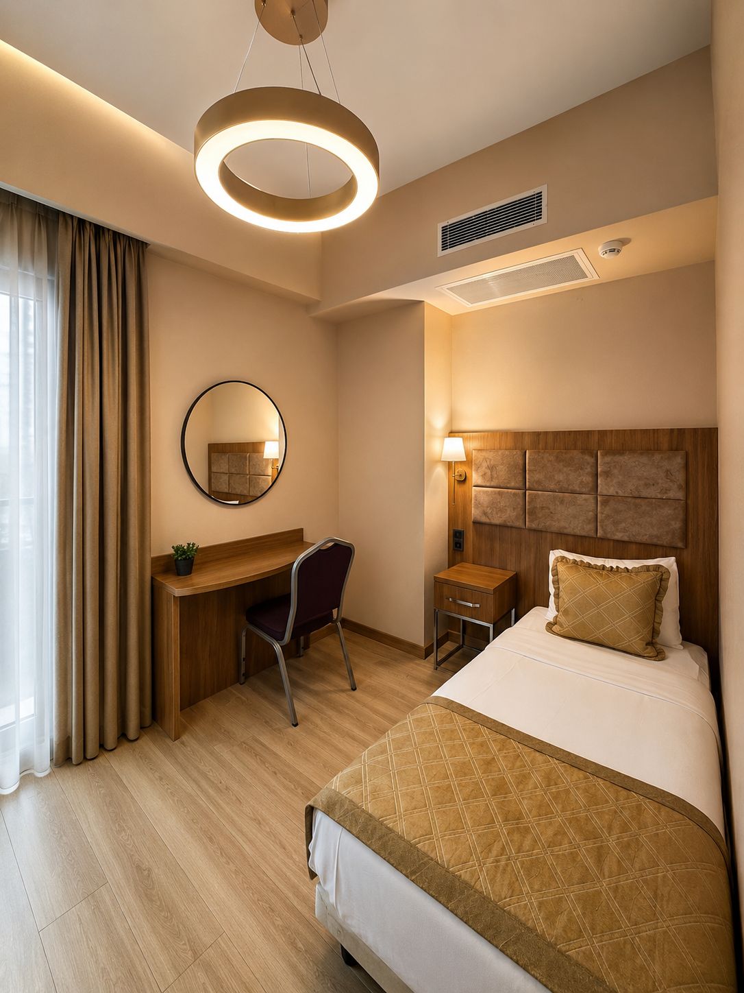 Habitación de hotel con cama, escritorio, silla y lámpara circular.
