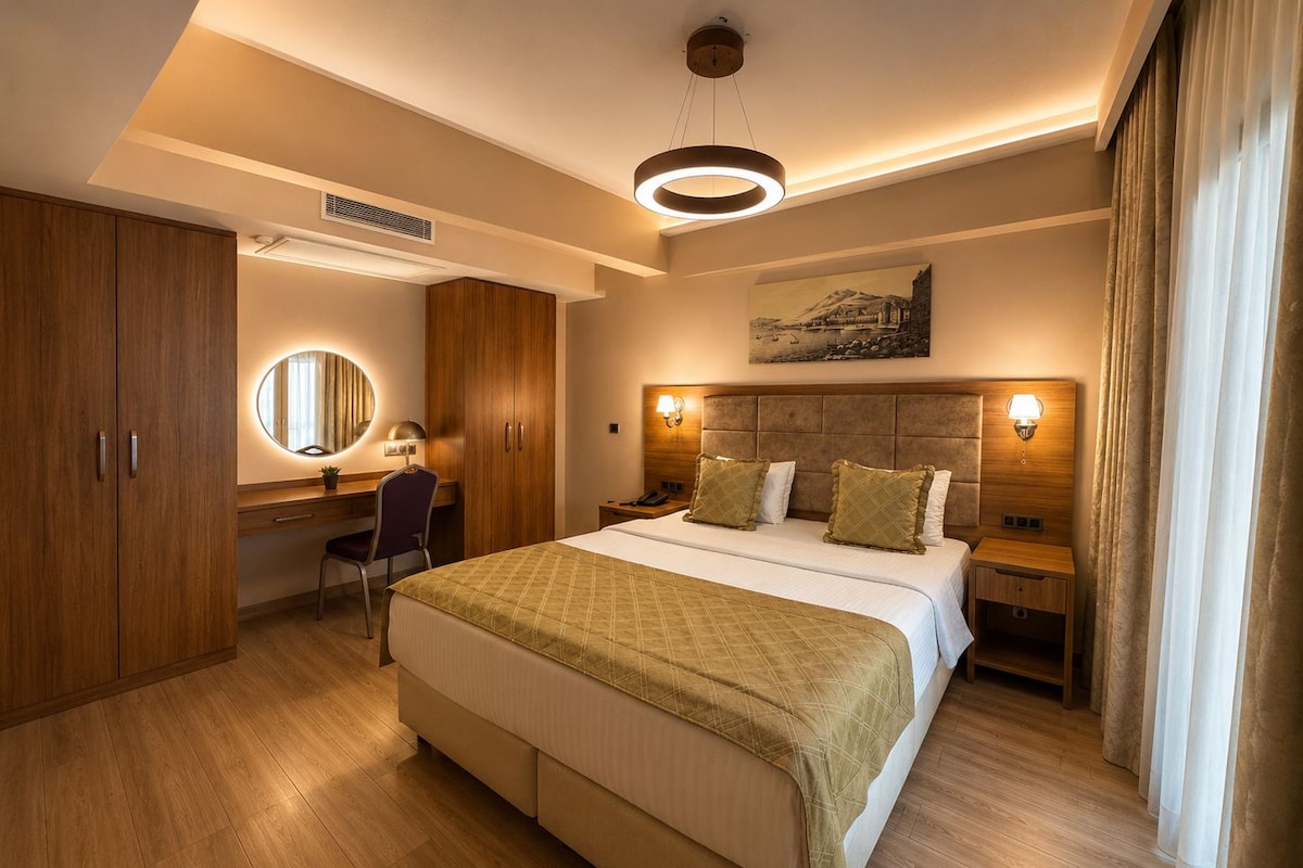 Una habitación de hotel con una cama grande, un escritorio, una silla, un espejo y un cuadro en la pared.