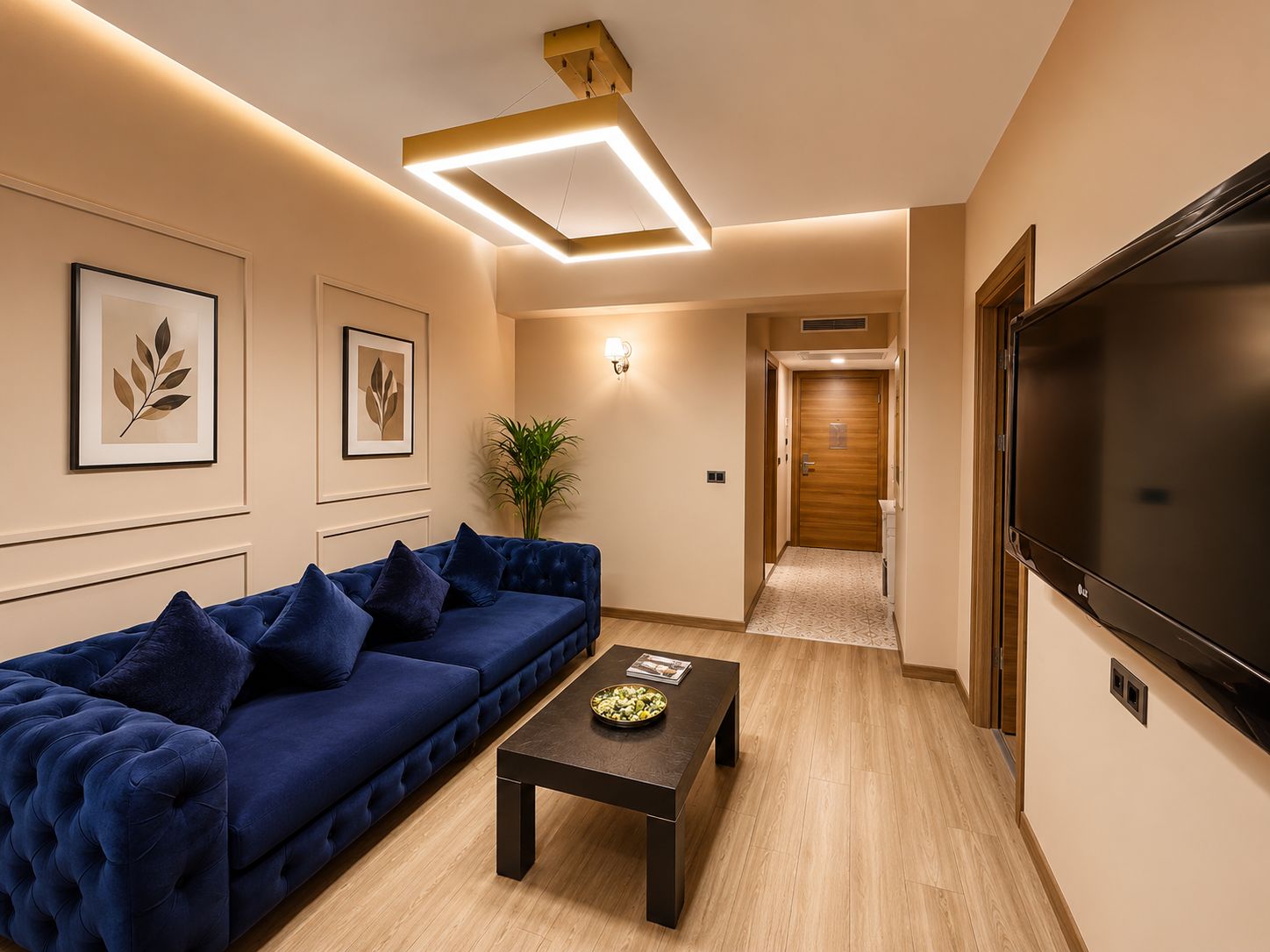 A modern living room with a blue sofa, a coffee table, a flat-screen TV, and framed artwork on the walls.